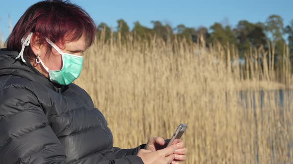 A Lady in Her Face Mask Holding Her Phone During a Life Quarantine