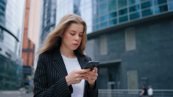 Beautiful Young Woman Using Smartphone Walking Through City Street Day Light alt