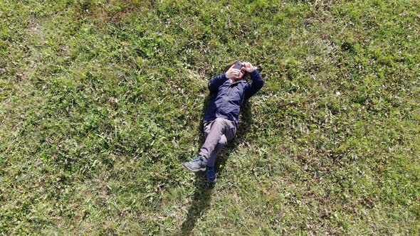 Man Laying on the Grass and Making Selfie Aerial Shot
