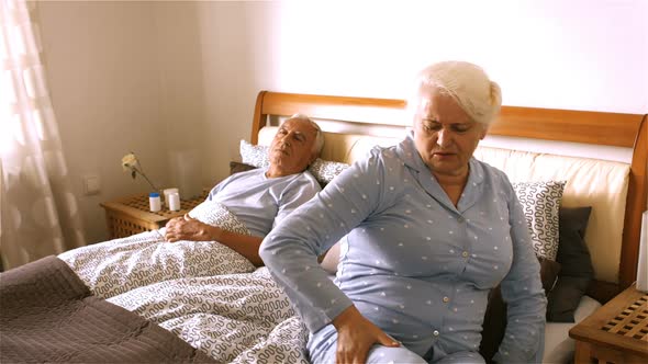 Senior woman suffering from backache sitting on bed alt