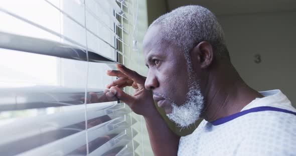 African american male patient looking at window in hospital room smiling alt