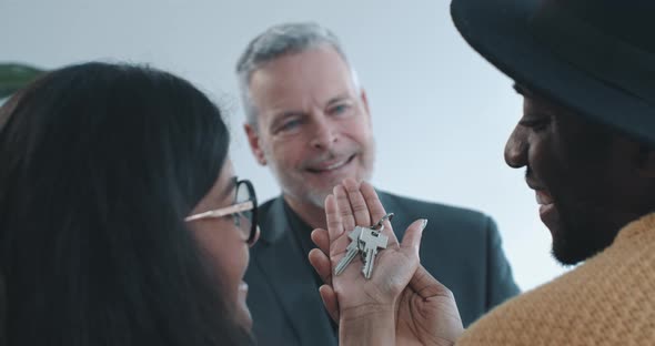 Close up shot of multi ethnic couple holding keys to new home over shoulder view alt