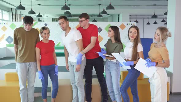 Young Man Choking with Male Instructor Standing Behind Performing Heimlich Maneuver Indoors alt