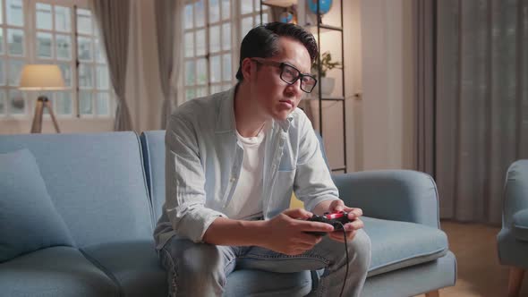 Bored Asian Man Using Joystick Playing A Game At Home alt