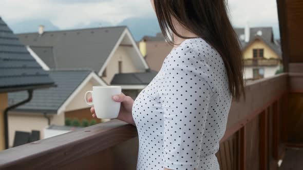 Close Up Young Woman Drinking From a White Cup on the Balcony with Amazing View on the Mountains and alt