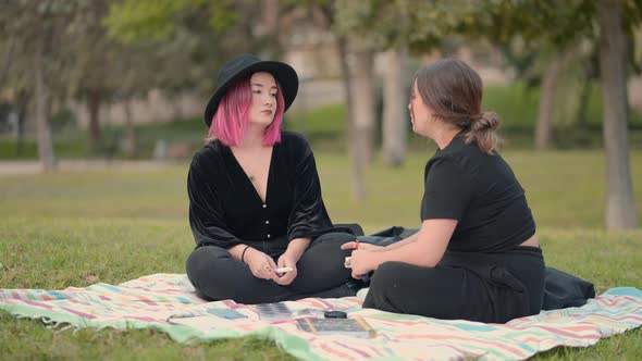 Caucasian Girls Dialoguing While Sitting on the Grass in the Park alt