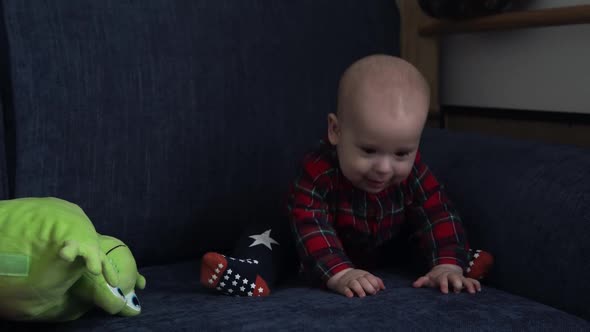 Happy Smiling Baby Sitting on Blue Sofa Playing with Toys Looking at Camera Cute Active 7 Month Old