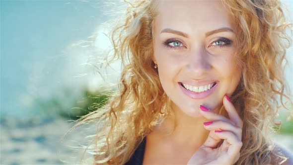 Close-up of a Beautiful Young Woman Smiling at the Camera. Sunny Day at the Beach Near the Sea alt