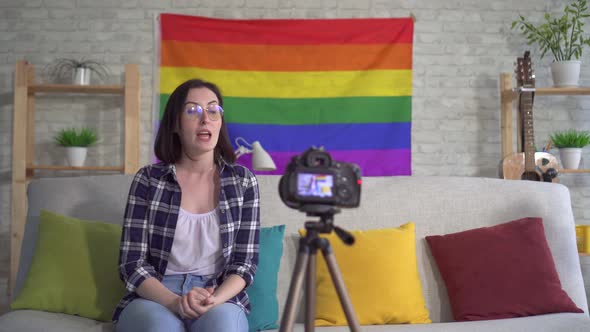 Young Woman Blogger in the Shirt on the Background of the Flag of the LGBT Records Video alt
