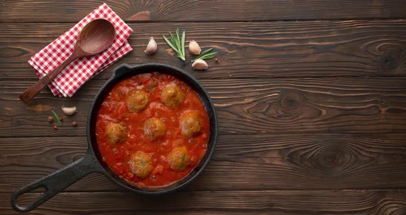 Meat balls in bubbling hot tomato sauce in black pan
