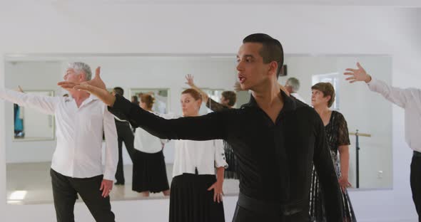 mixed race male dance teacher taking a ballroom dancing class at a dance studio alt