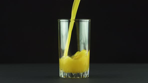 Juice Pouring Into Glass Isolated on Black Background alt