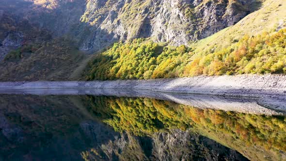 Lac d'Oô reflecting artificial lake in the French Pyrenees with view of the Oo waterfall, Aerial pan alt