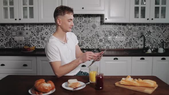 Man Using Tablet and Drinking Juice alt
