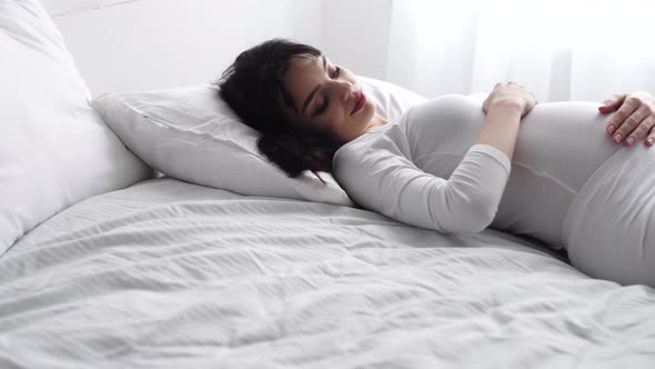 Pregnant Beautiful Woman Lying On Bed And Caressing Baby Belly