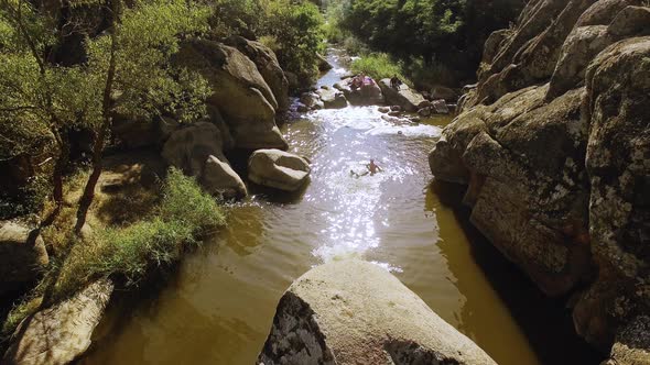 Male Jumping From Rock to the River Where People Swiming Bathing with Husky Dog alt