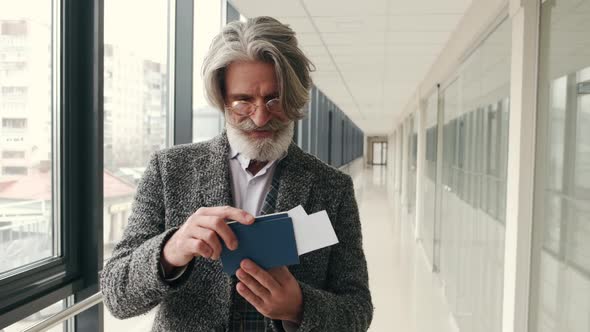 Elegant Senior Man Checking Passport and Bording Pass at Corridor in the Airport alt