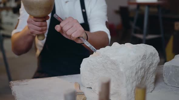 Male Hands which Holding the Mallet ans Chisel Knocking off the Shape of Future Sculpture alt