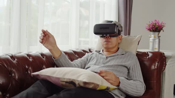 Senior man playing in virtual reality glasses at home