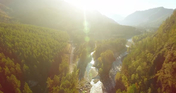 Mid Air Flight Over Fresh Mountain River and Meadow at Sunny Summer Morning. Rural Dirt Road Below. alt