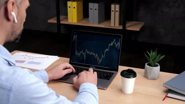 Adult Man Stock Trader Broker Uses Laptop with Stock Exchange Chart in Office alt