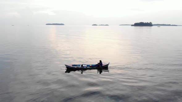 Aerial view of fisherman's silhouette paddling his small boat in the ocean