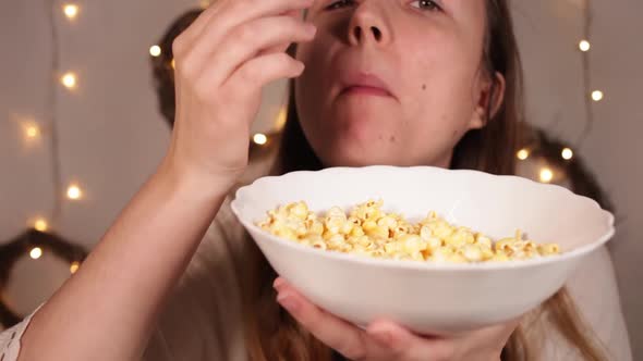 Woman Eats Popcorn Christmas Lights on a Blury Background Funny Stuffs Her Mouth with Popcorn