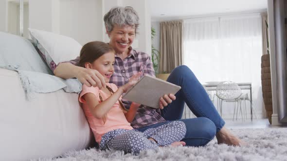 Senior woman using digital tablet with her granddaughter alt