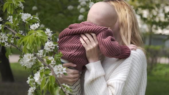 portrait of a caucasian mom with a baby in her arms in a blooming garden