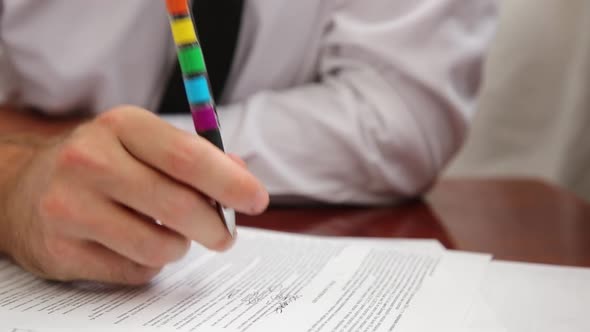 Man In Office With Tie Works, Fills Out Paperwork With Pen With Rainbow Lgbt