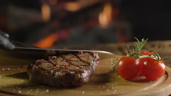 Slicing Meat Steak on Wooden Board over Fire Background