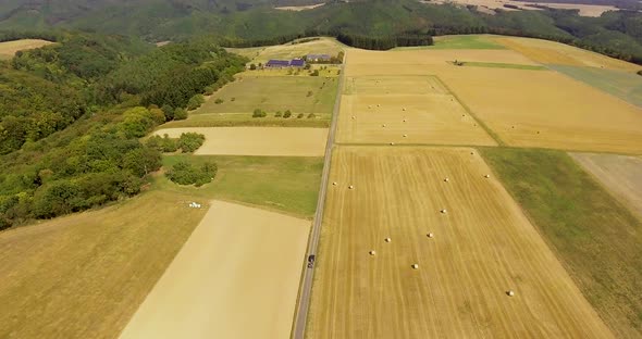 Flight with a DJI Phantom 4 Drone above a rural road in an agricultural area while car is driving on alt