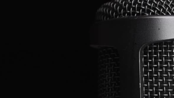 Studio Condenser Microphone Rotates on Black Background with Place for Text alt