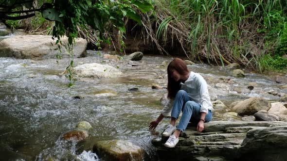 A young asian woman playing and splashing waterfall in the jungle