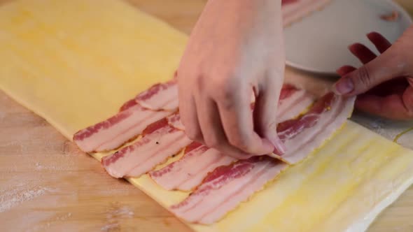 Putting smoked bacon on the sheet of raw puff pastry alt