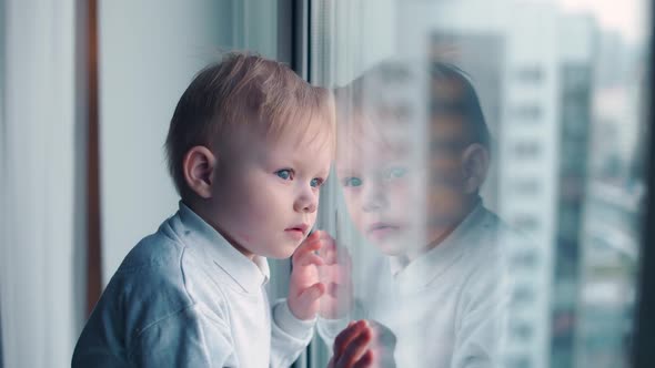 Little Kid on Home Quarantine Looking Out the Window Selfisolation in the Context of the Coronavirus alt