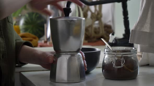 Woman make a coffee in moka pot in kitchen alt