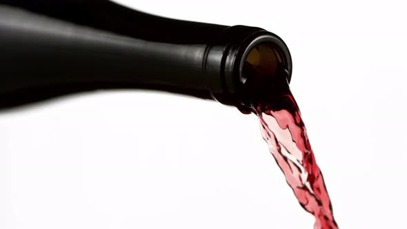 Super Slow Motion Detail Shot of Pouring Red Wine From Bottle Isolated on White at 1000Fps alt