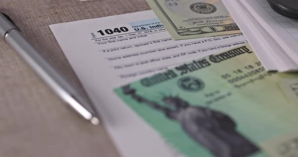 Stimulus Economic Tax Return Check and USA Currency Hundred US Dollar Bills 1040 U alt