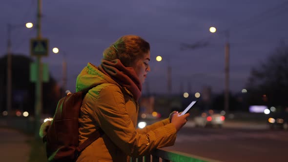 Woman Using Phone at the Night City Near Road Traffic alt