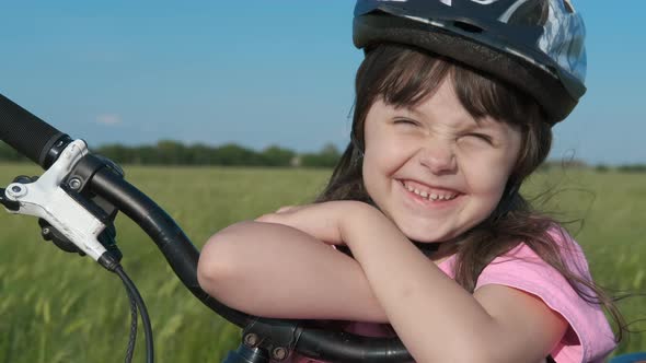 Child with a bike in a meadow.  alt