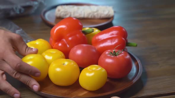 Hands Beautifully Spread Tomatoes and Sweet Pepper on Wooden Round Cutting Board alt