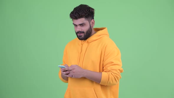 Happy Young Overweight Bearded Indian Man Using Phone and Getting Good News alt