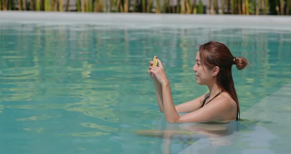Woman take photo on cellphone in swimming pool