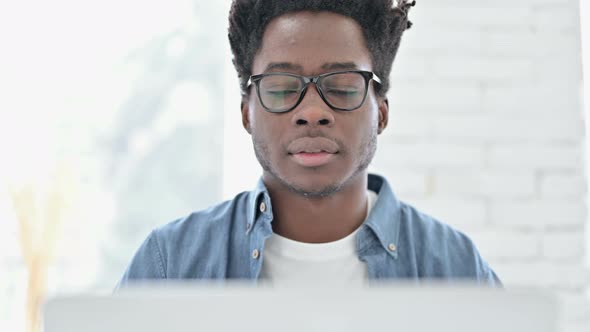 Portrait of Young African Man Smiling and Working on Laptop alt