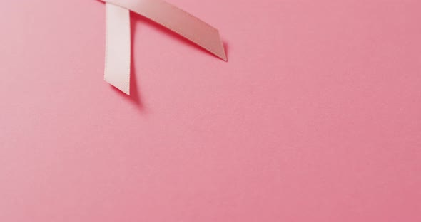 Video of pink breast cancer ribbon on pale pink background alt