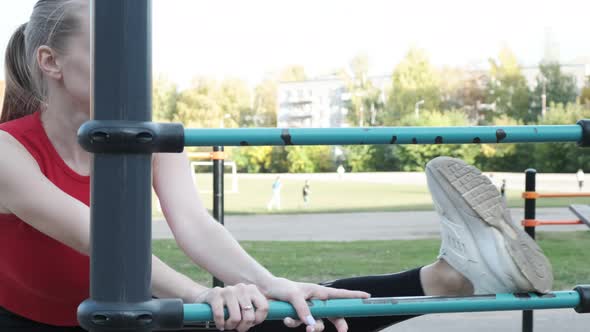 Slim Pretty Female in Sportswear Stretching Legs at Sports Ground Before Workout alt