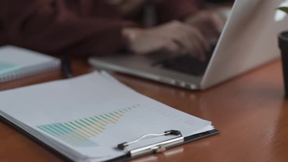 Close Up Statistics Charts and Hand Working with Business Documents on Office Table with Laptop alt