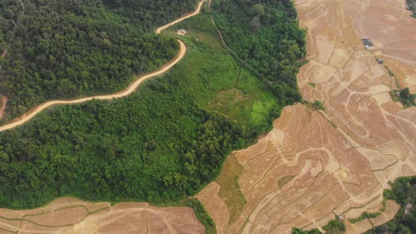 Aerial: flying over rice paddies unique valley scenic cliffs rock pinnacles tropical jungle Laos alt