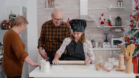 Grandparents Helping Granddaughter Preparing Traditional Homemade Dough alt